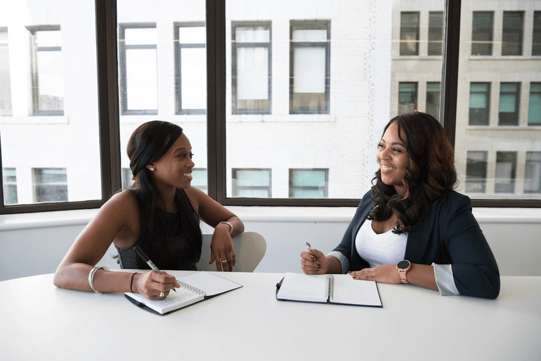 Two women discussing ideas at a table by the window