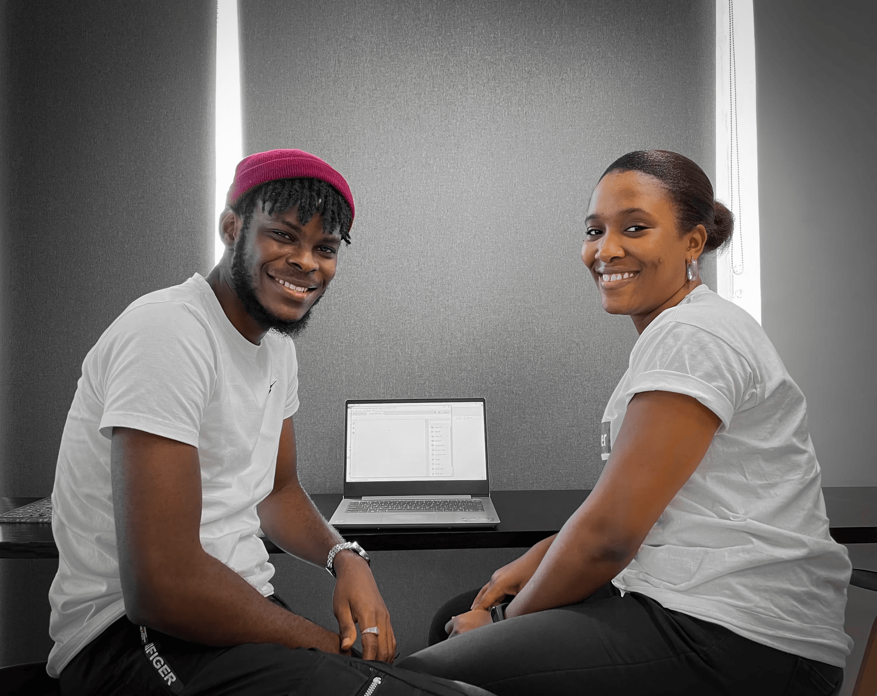 Two teammates smiling together while sitting at a desk