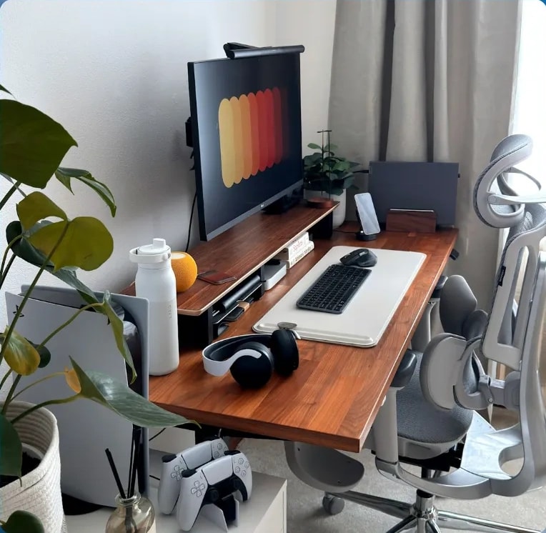 A desk with a monitor, keyboard and plants, framed by blue clouds